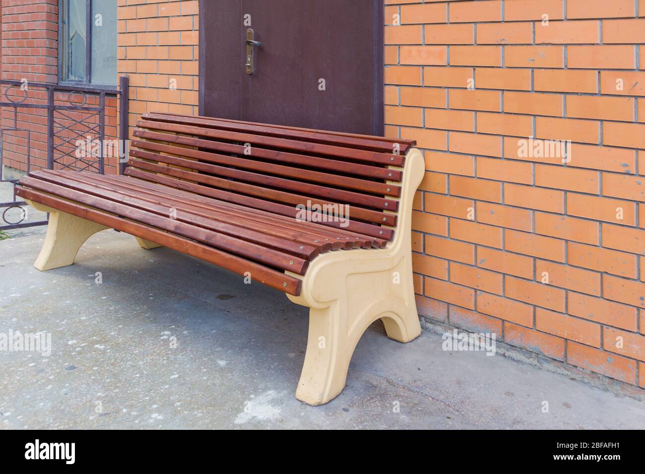 Un banc en bois assis devant la porte sur un bâtiment en brique avec une fenêtre cassée. Banque D'Images