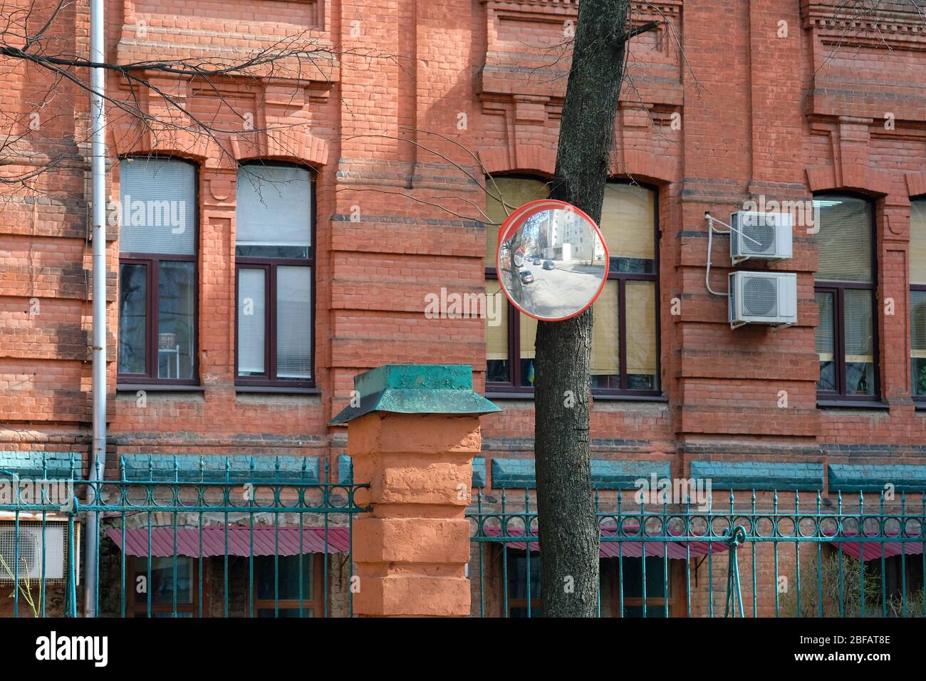 Miroir panoramique de sécurité monté sur un tronc d'arbre dans la ville. Miroirs de sécurité sphériques pour la surveillance des zones mal visibles de la route. Banque D'Images