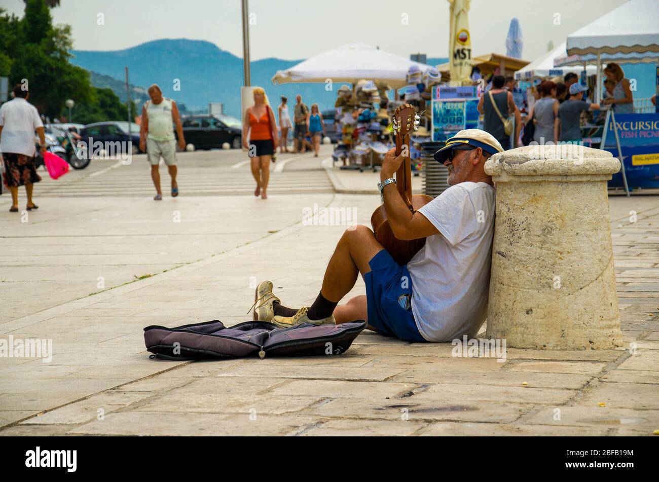 Trogir, Croatie - 17 mai 2016 : musicien de rue avec guitare et casquette de marin est assis dans la rue dans la ville portuaire Banque D'Images