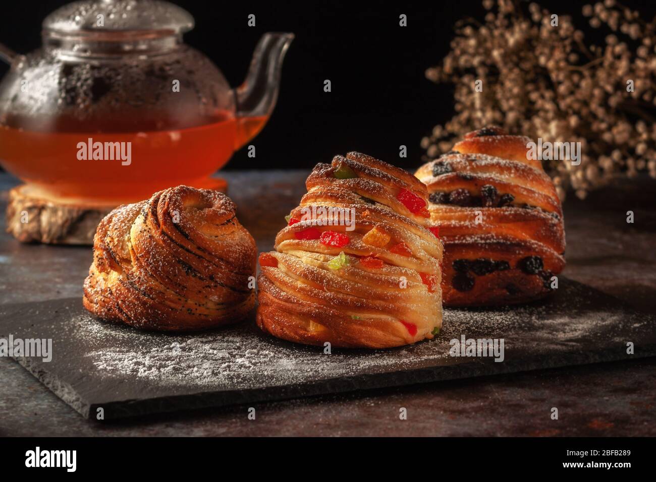Kraffins aux raisins secs, fruits confits et graines de pavot, arrosés de sucre en poudre. Banque D'Images