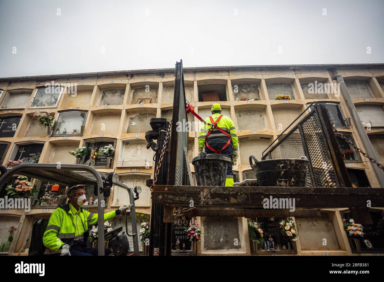 Un gravedigger exploite un chariot élévateur avec son partenaire se préparant à fermer la niche pendant les funérailles. Le Covid-19 rend les funérailles difficiles, la situation exige que les travailleurs portent des masques et soient forcés de limiter l'accès, dans certains cas les cérémonies sont sans membres de la famille. Banque D'Images