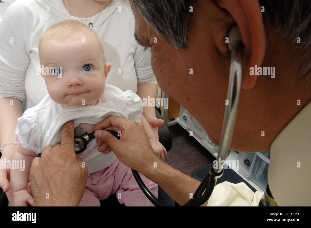Un GP écoute les battements cardiaques d'un bébé à l'aide d'un stéthoscope (modèle libéré) Banque D'Images