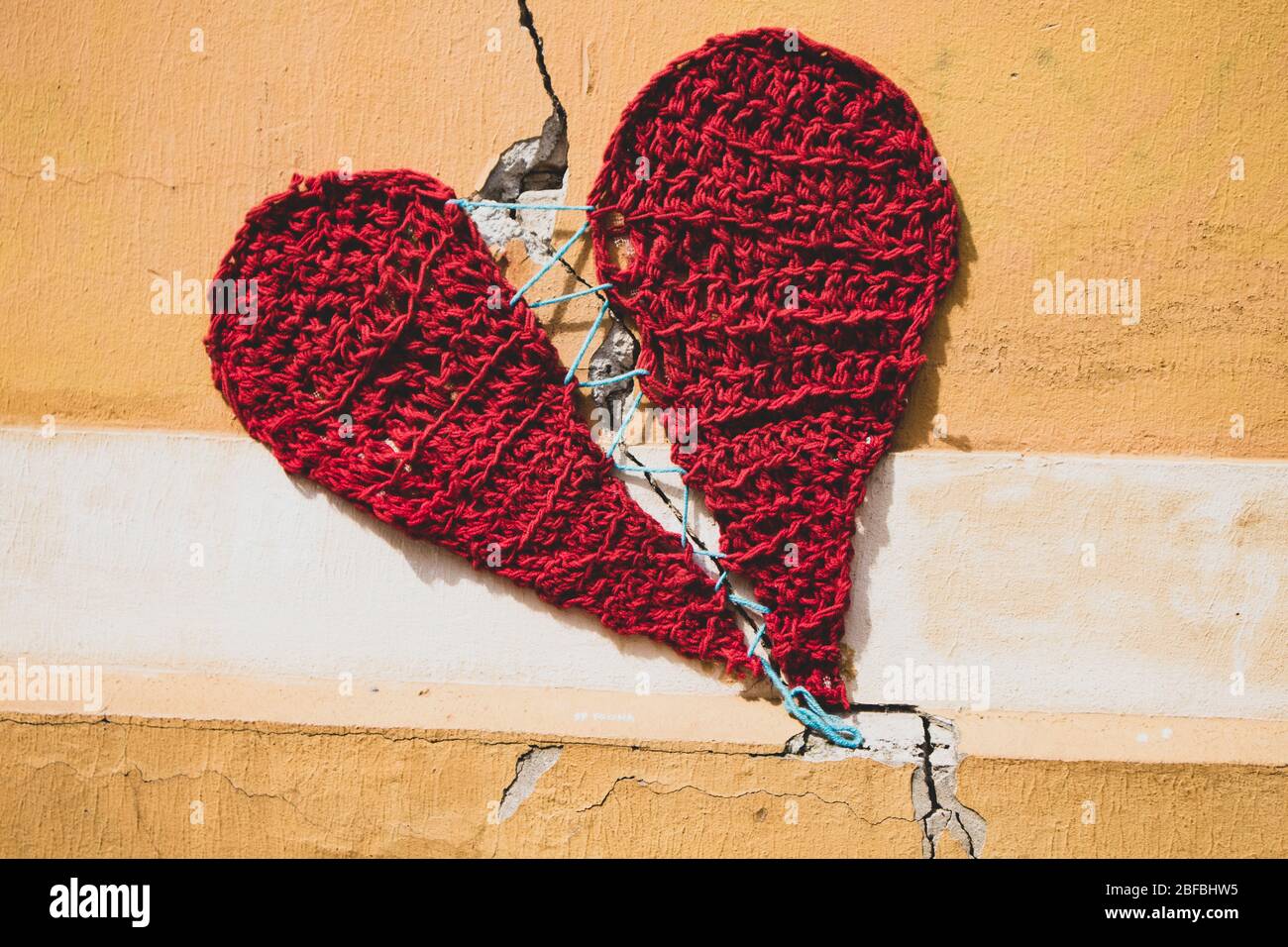 Coeur rouge cousu autour de la fracture de mur sur la façade beige, filmé dans les rues de Zagreb Banque D'Images