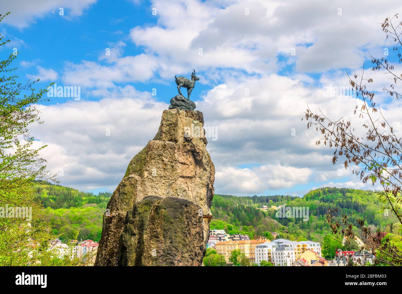Statue du chamois Socha Kamzika à Deer Jump Jeleni Skok Lookout avec Karlovy Vary (Carlsbad) de beaux bâtiments colorés et des collines de la forêt de Slavkov backg Banque D'Images