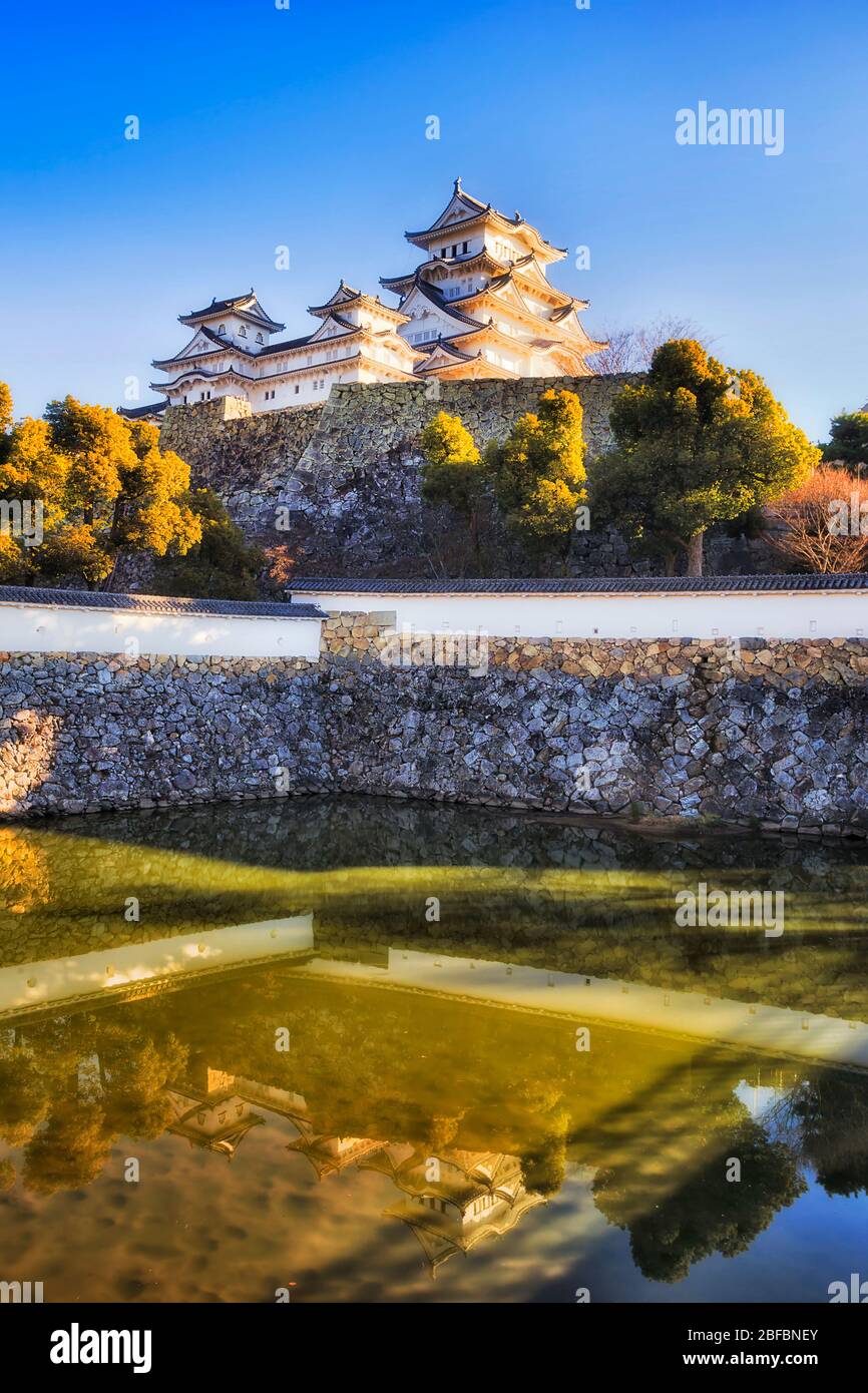 Eau gémissement autour des murs en pierre de la tour blanche principale à Himeji, une journée ensoleillée contre le ciel bleu. Banque D'Images
