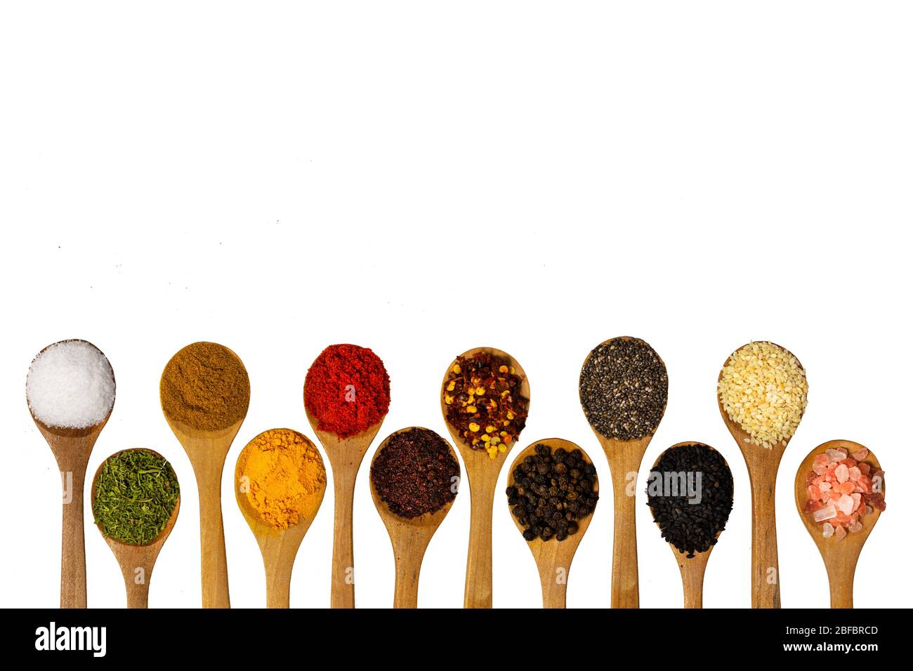 Composition avec différentes épices aromatiques dans des cuillères en bois sur fond blanc Banque D'Images