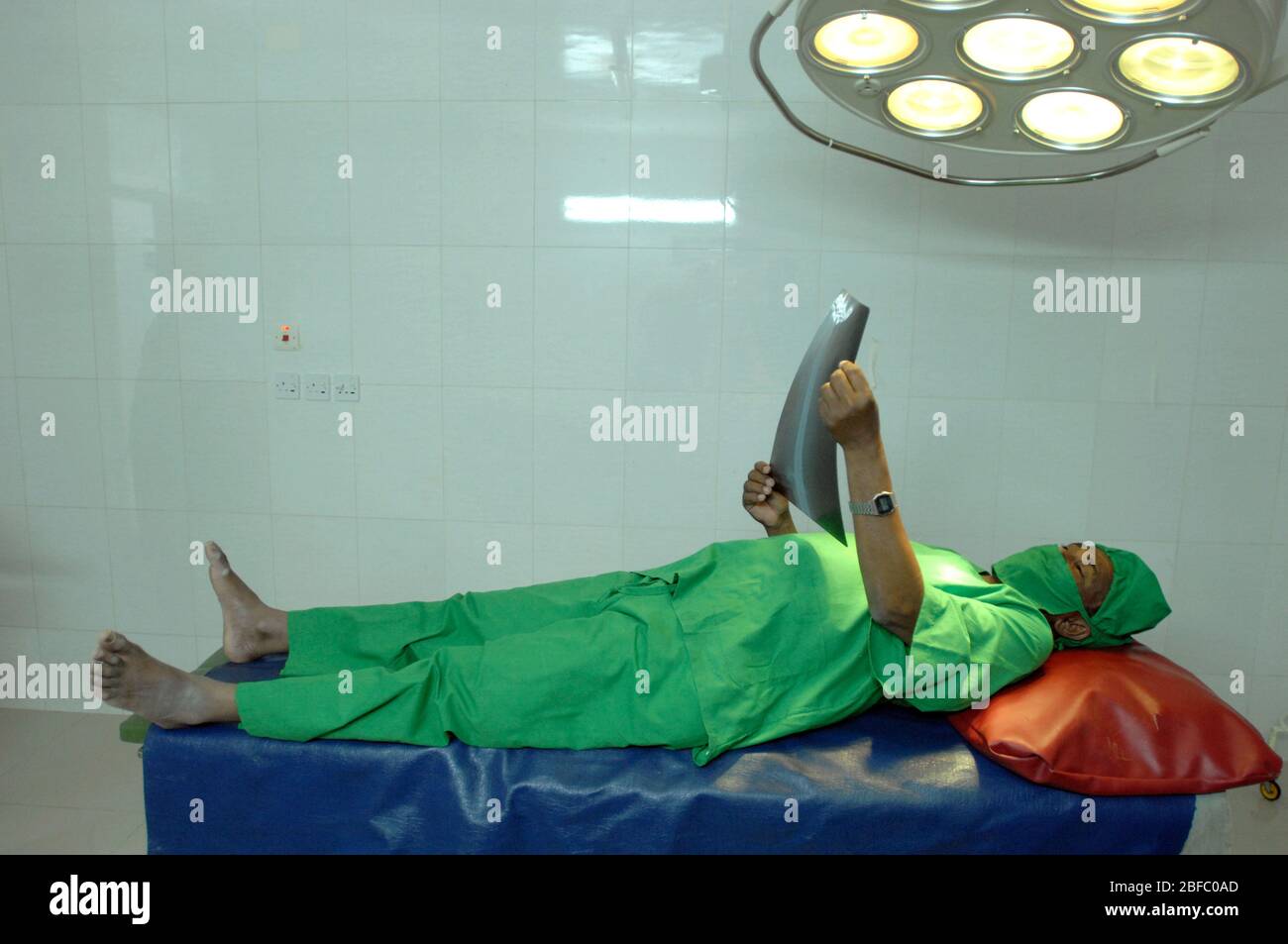 Un médecin pose une table d'opération tout en regardant une radiographie. Banque D'Images