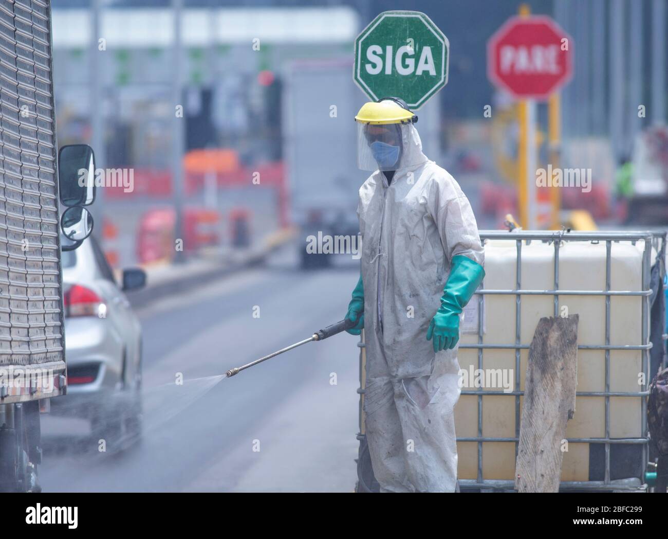 Bogota, Colombie. 17 avril 2020 : une personne en combinaison et une combinaison de biosécurité ont effectué une procédure de désinfection sur les véhicules traversant la région. Au moyen d'un arroseur avec hypochlorite de sodium, les pneus de voiture passent par ce processus, au péage des Andes, au nord de la ville de Bogota: Daniel Garzon Herazo/ZUMA Wire/Alay Live News Banque D'Images