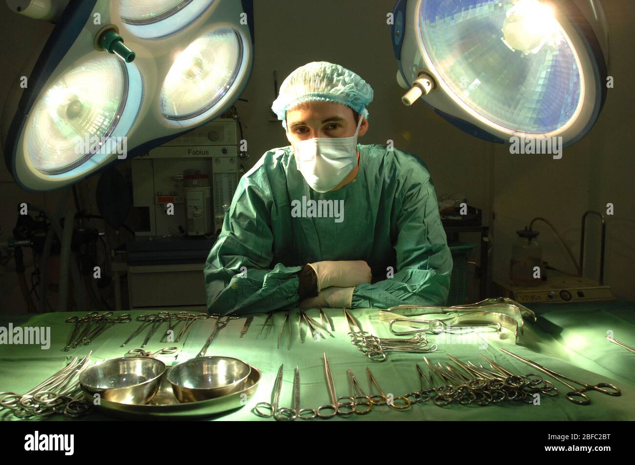 Un chirurgien masqué penche sur une rangée d'outils chirurgicaux stériles dans un hôpital Banque D'Images