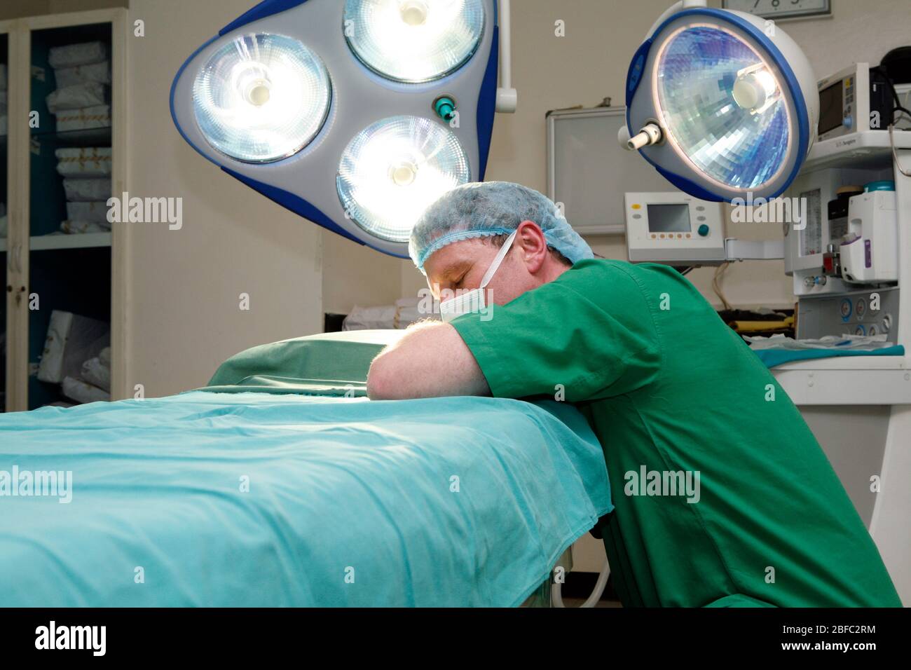 Un chirurgien fatigué sur travaillé pontant pour se reposer sur une table d'opération Banque D'Images
