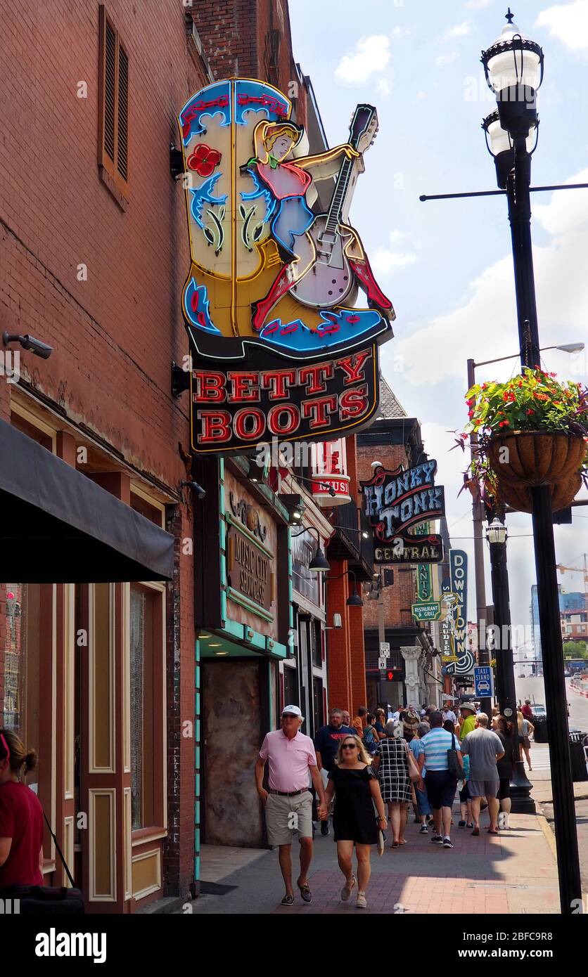 NASHVILLE, TENNESSEE - 25 JUILLET 2019: Les touristes se promènent le long de Nashville's Broadway sous des enseignes au néon aux couleurs vives pour les magasins et les salons, y compris Banque D'Images