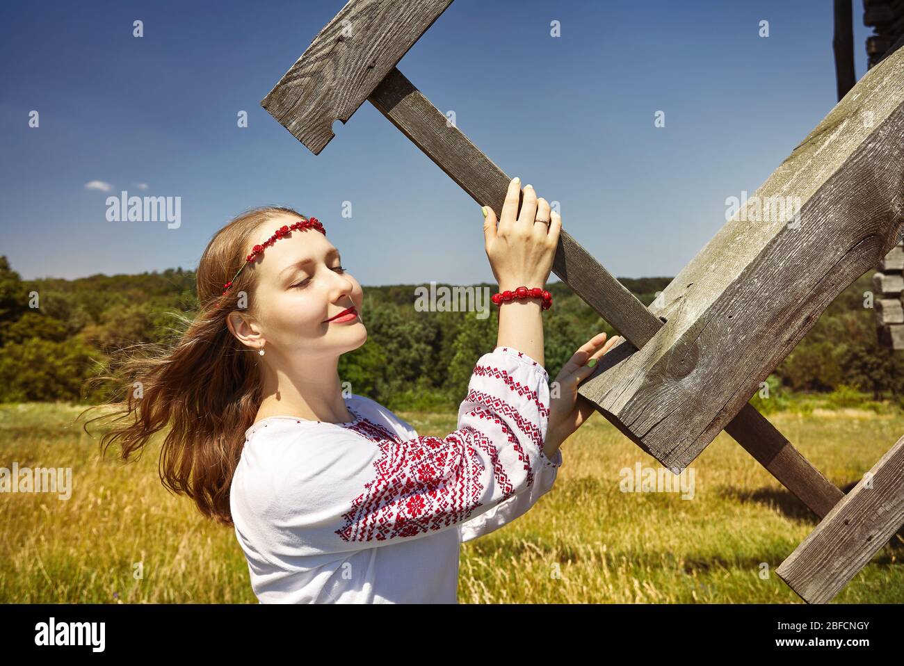 Portrait de la belle jeune fille ukrainienne holding blade de moulin à vent en bois blanc en chemise ethnique au musée d'architecture à Pirogovo. Kiev, Ukraine Banque D'Images