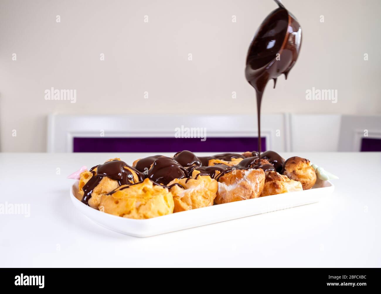 Pourvoirie au chocolat. Dessert sucré sur une assiette blanche. Profiteroles maison avec sauce crème et chocolat. Banque D'Images