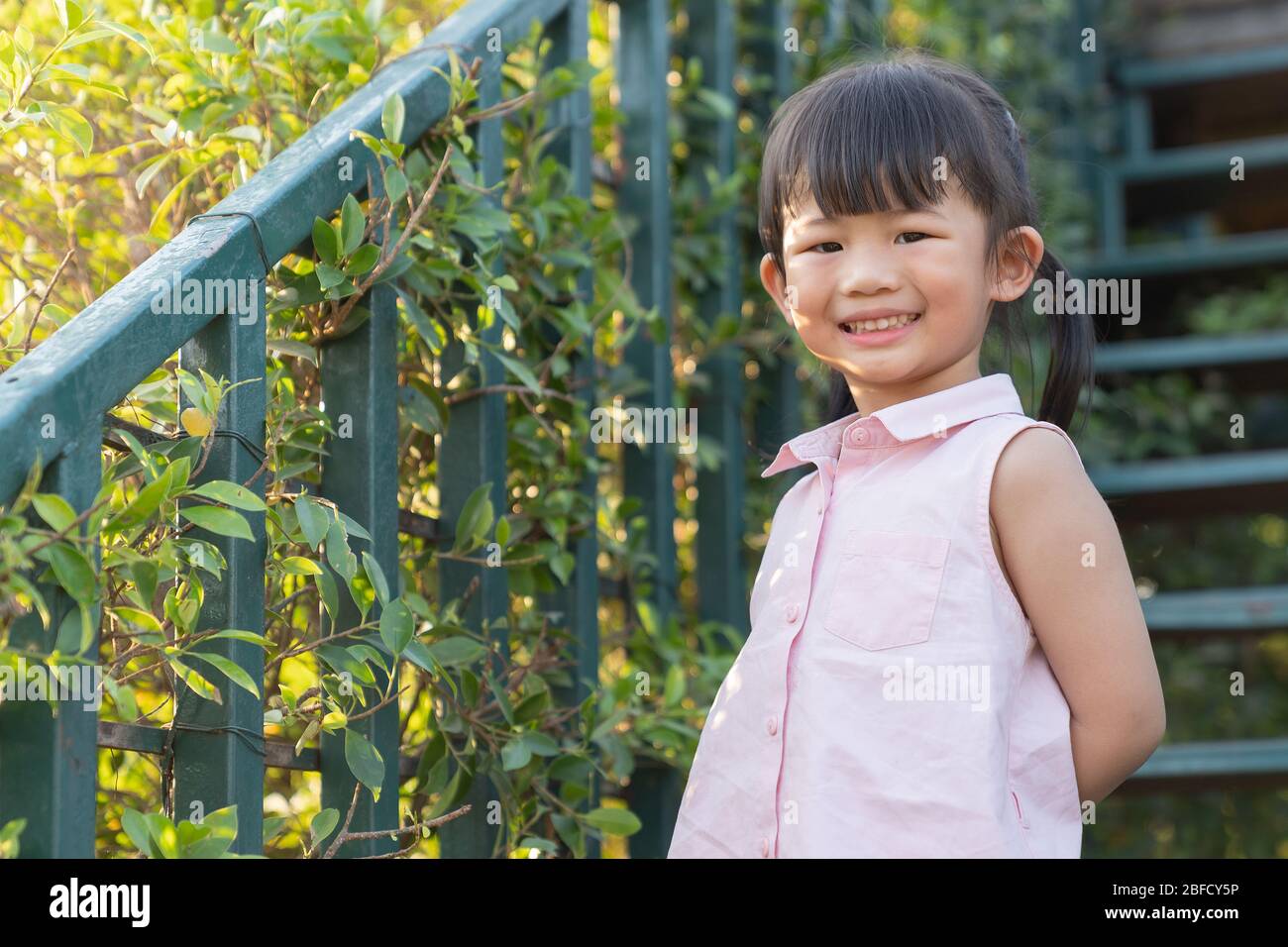 Portarie fille enfant. Petite fille asiatique mignon affiche dans le jardin. Bonne petite fille sur le champ des fleurs en été. Banque D'Images