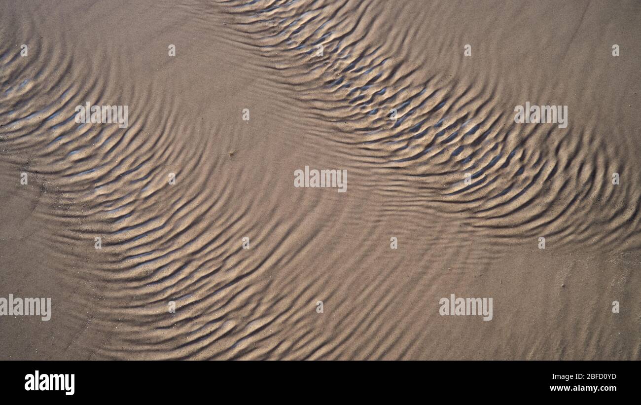 Vue rapprochée des ondulations sur la surface de l'eau créée par un vent fort dans le sable sur une plage Banque D'Images