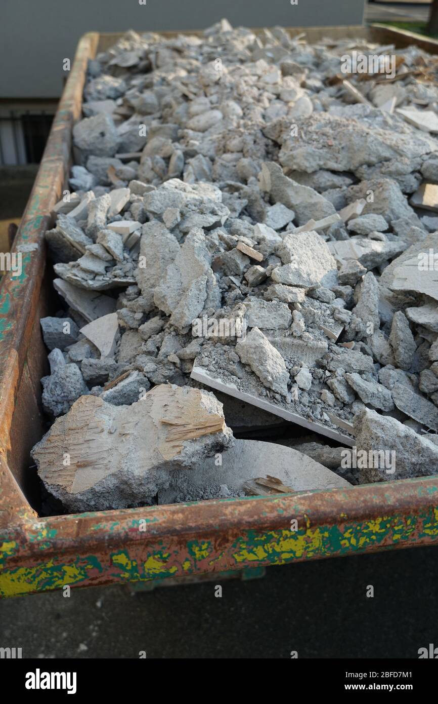 Débris de construction dans un grand, vieux, contenant rouillé. Des morceaux de mortier, du béton brisé et des séparateurs de bois remplissent tout le volume. Banque D'Images