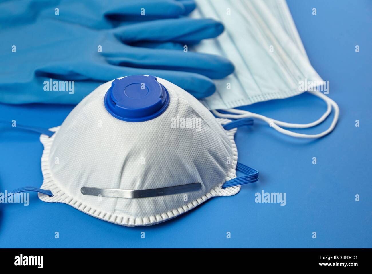 Masque respiratoire FFP2, masques chirurgicaux jetables et gants en caoutchouc sur fond bleu. Protection contre la pandémie de coronovirus COVID-19. Filterin blanc Banque D'Images