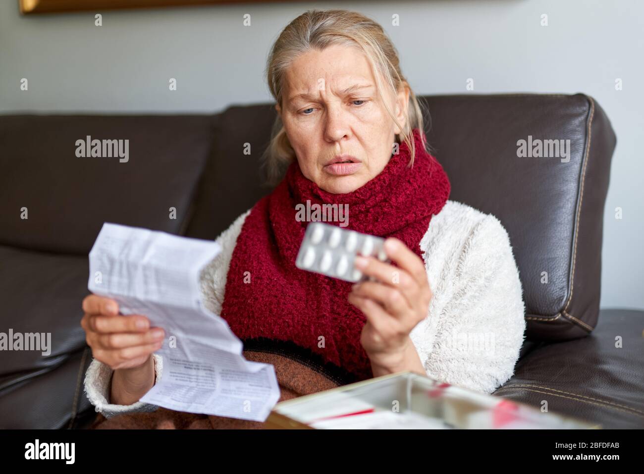 Femme mature prenant la médecine. Femme tenant le pack de Blister avec des pilules en main et lisant des instructions médicales. Femme aînée regardant l'instruction, tenir Banque D'Images