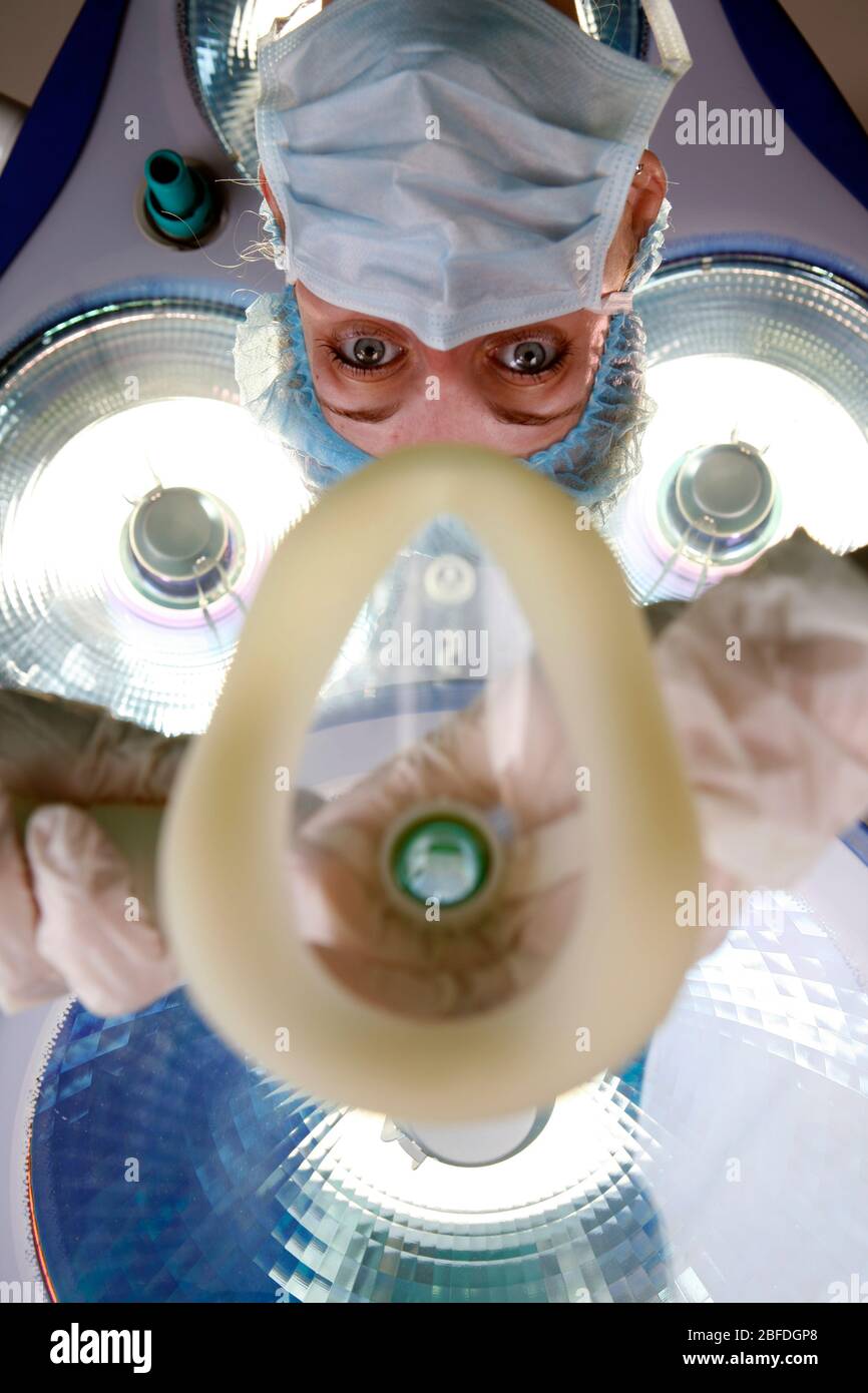 Un anesthésiste tient un masque respiratoire sous les feux de travail. Le patient souffle à travers le masque utilisé pour administrer le gaz à Banque D'Images