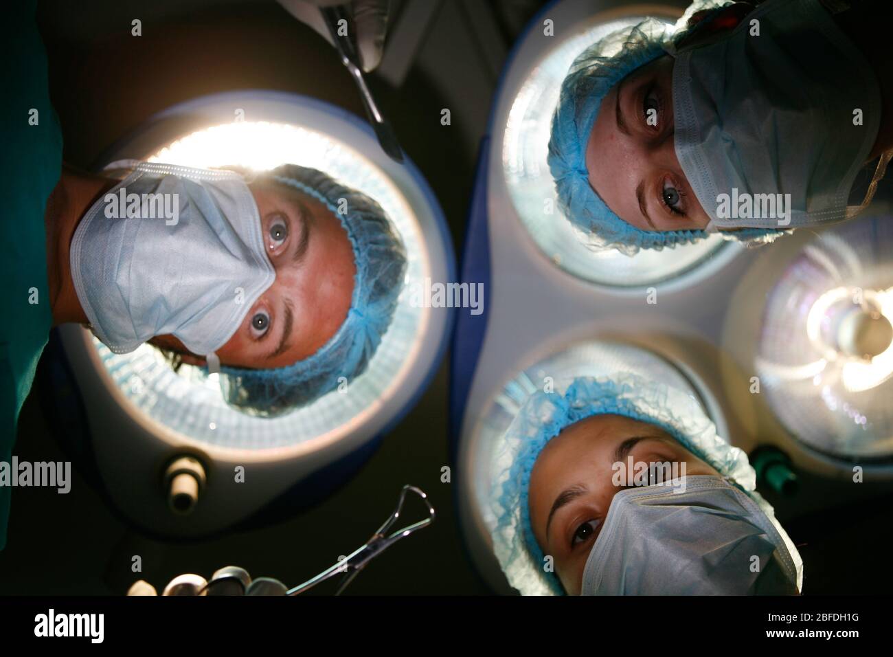 Vue des patients de l'équipe chirurgicale fonctionnant sous les lampes du théâtre Banque D'Images