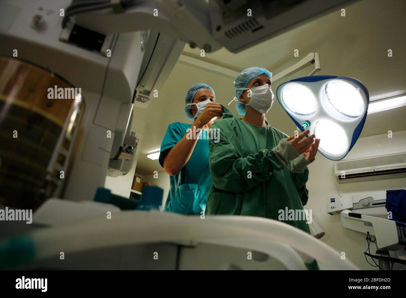 Un assistant aide le chirurgien avec ses vêtements de protection. Banque D'Images