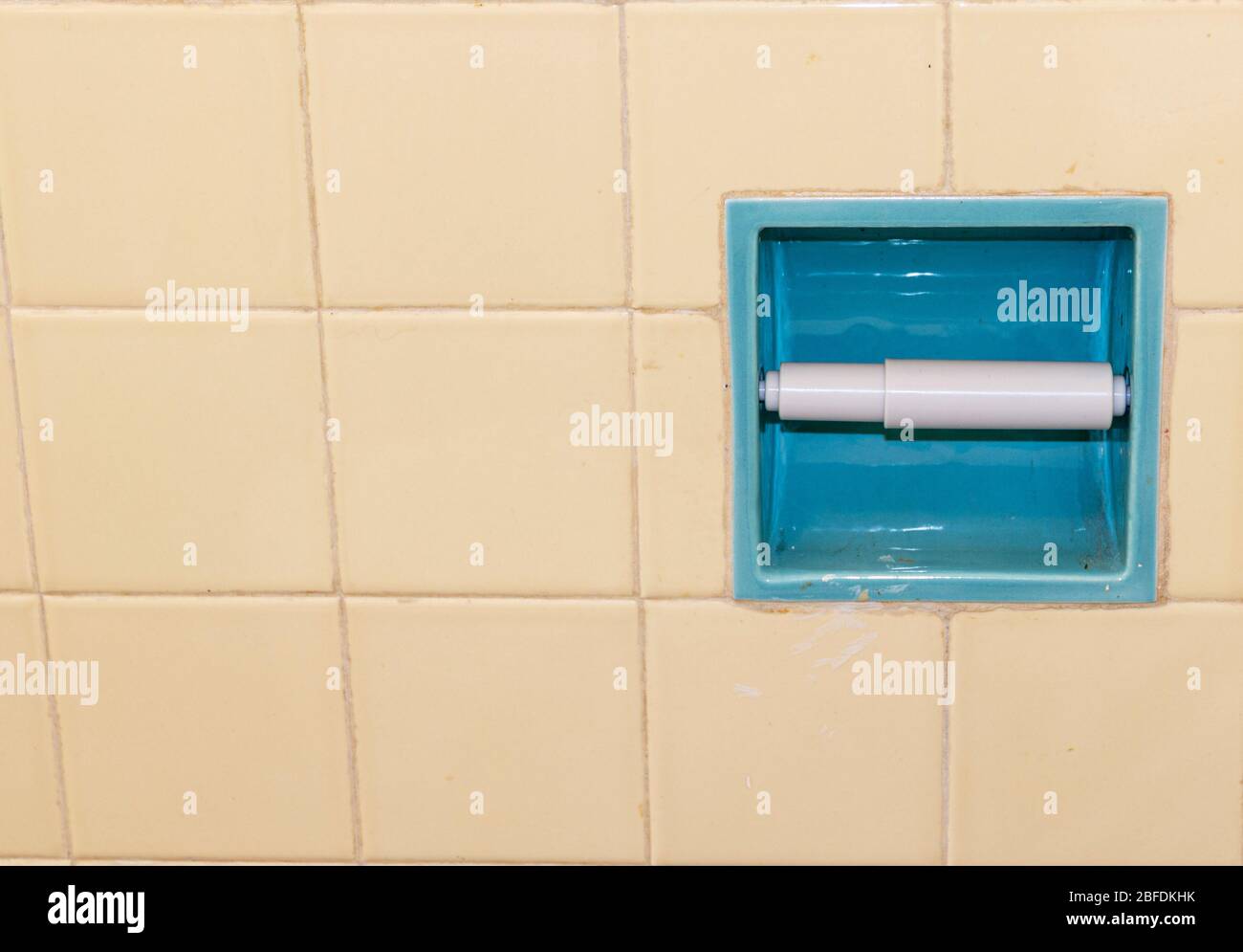 Un mur de salle de bains carrelée avec un support de papier toilette vide dû à la horde pendant l'éclosion de coronavirus. Banque D'Images