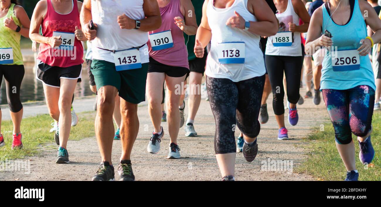 Un grand groupe de coureurs qui tournent vers la caméra lors d'une course sur piste d'été autour d'un parc national du lac Belmont. Banque D'Images