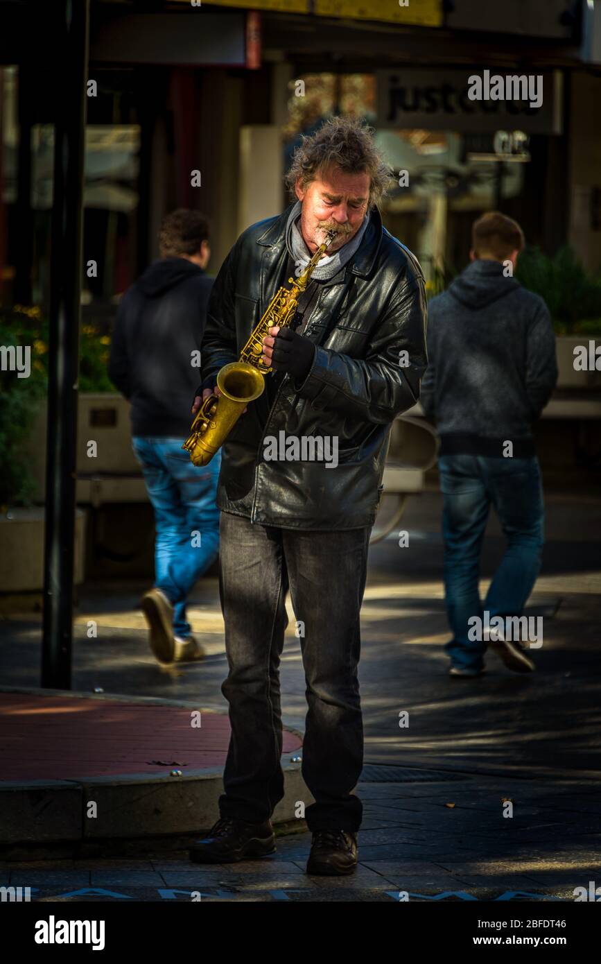 Launceston solo performance par une saxophoniste de rue revêtue d'une veste en cuir dans une lumière aux applis. Banque D'Images