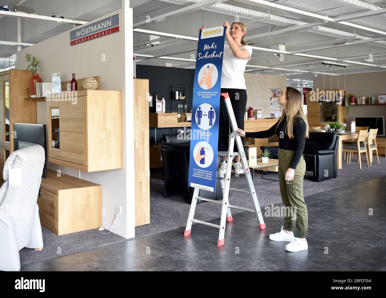 Bochum, Allemagne. 18 avril 2020. Ana Marija Pesic (l) et Lorena Marie  Thomas, décorateurs, accrochent des enseignes dans le magasin vide de  meubles Hardeck. Après la longue pause due à la pandémie