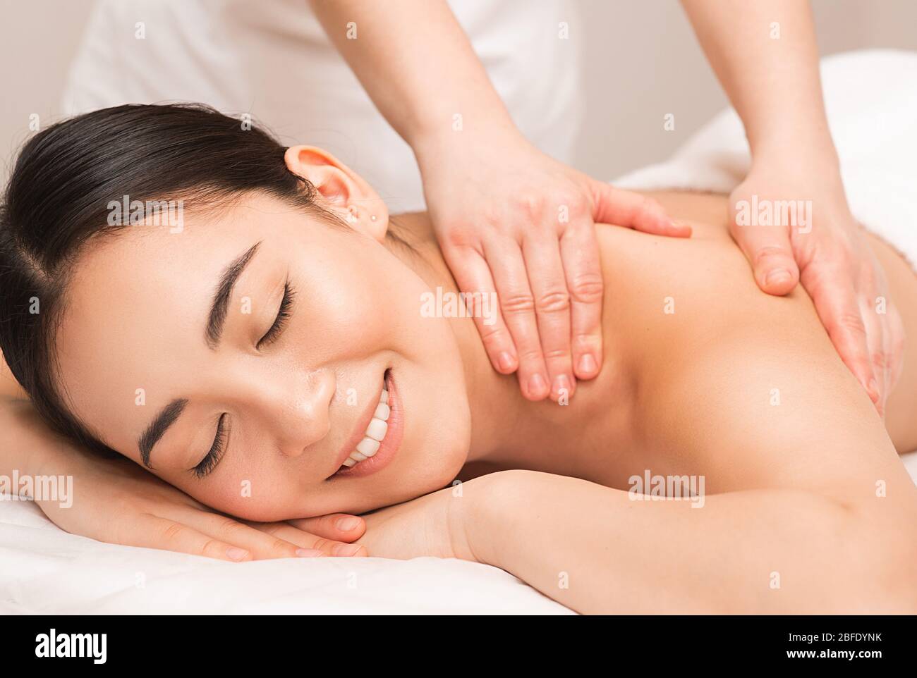 Massage thaïlandais. Portrait femme asiatique profitant d'un massage du dos au spa. Banque D'Images