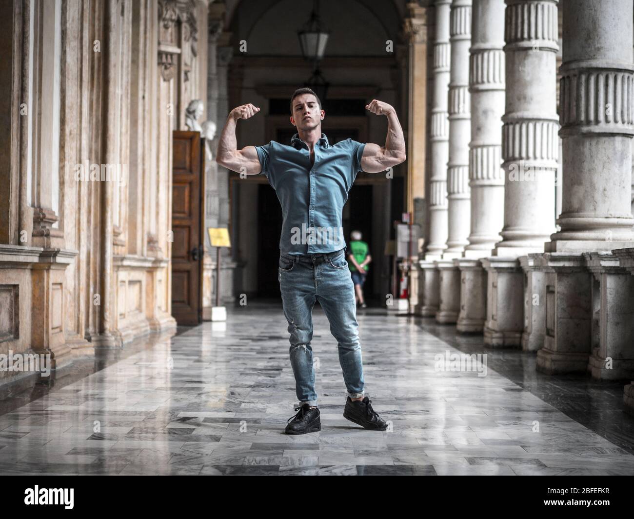 Un jeune homme sérieux fléchit les muscles dans le couloir Banque D'Images