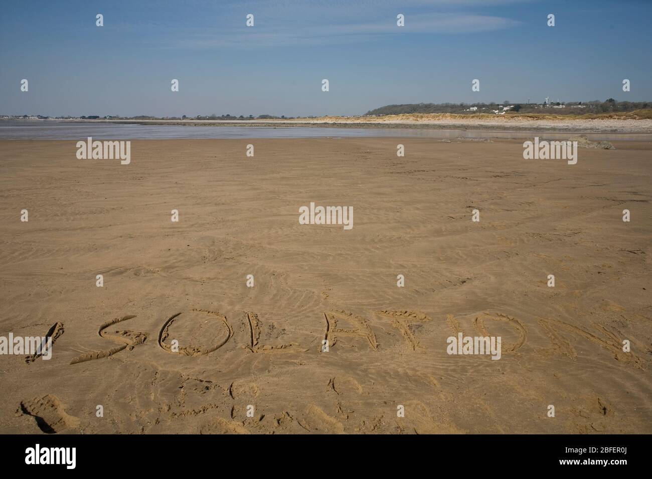 Le mot isolation inscrit sur le sable de la partie de Newton Beach au-delà des roches noires pendant les premiers jours du verrouillage pandémique Banque D'Images