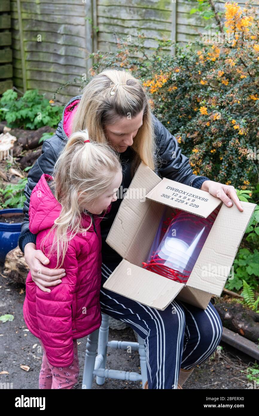 La mère et la fille inspectent les visières livrés dans des boîtes qui seront distribuées aux travailleurs de santé locaux du sud du pays de Galles pendant la crise de la pandémie de Covid. Banque D'Images