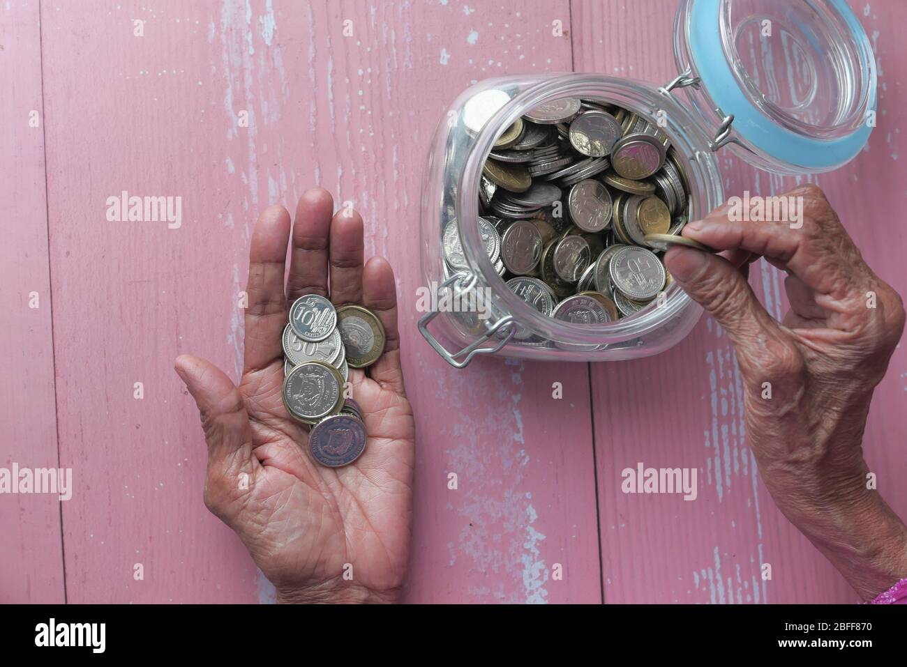 femmes âgées économisant des pièces dans un pot. Banque D'Images