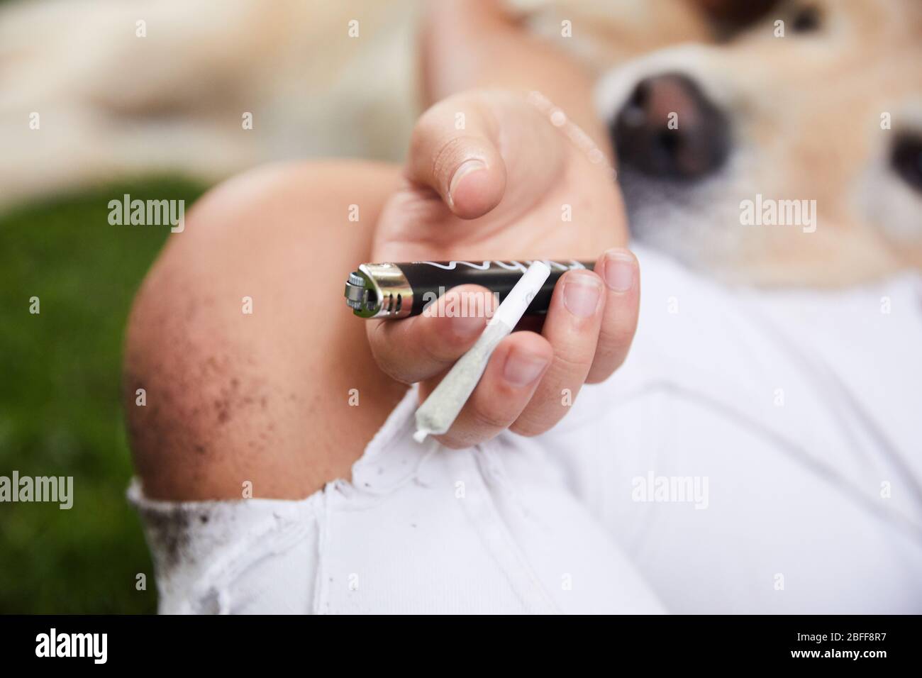 Une femme se détend dans son jardin arrière et se prépare à fumer un joint de prétournoi de marijuana Banque D'Images