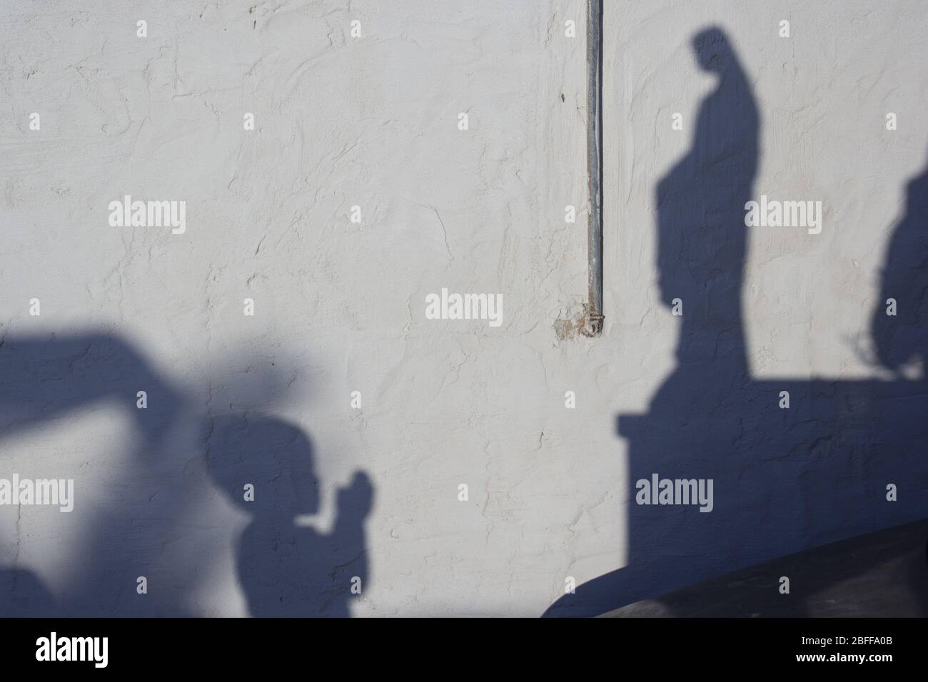 Ombre d'un enfant priant à la statue de la Madonna Banque D'Images