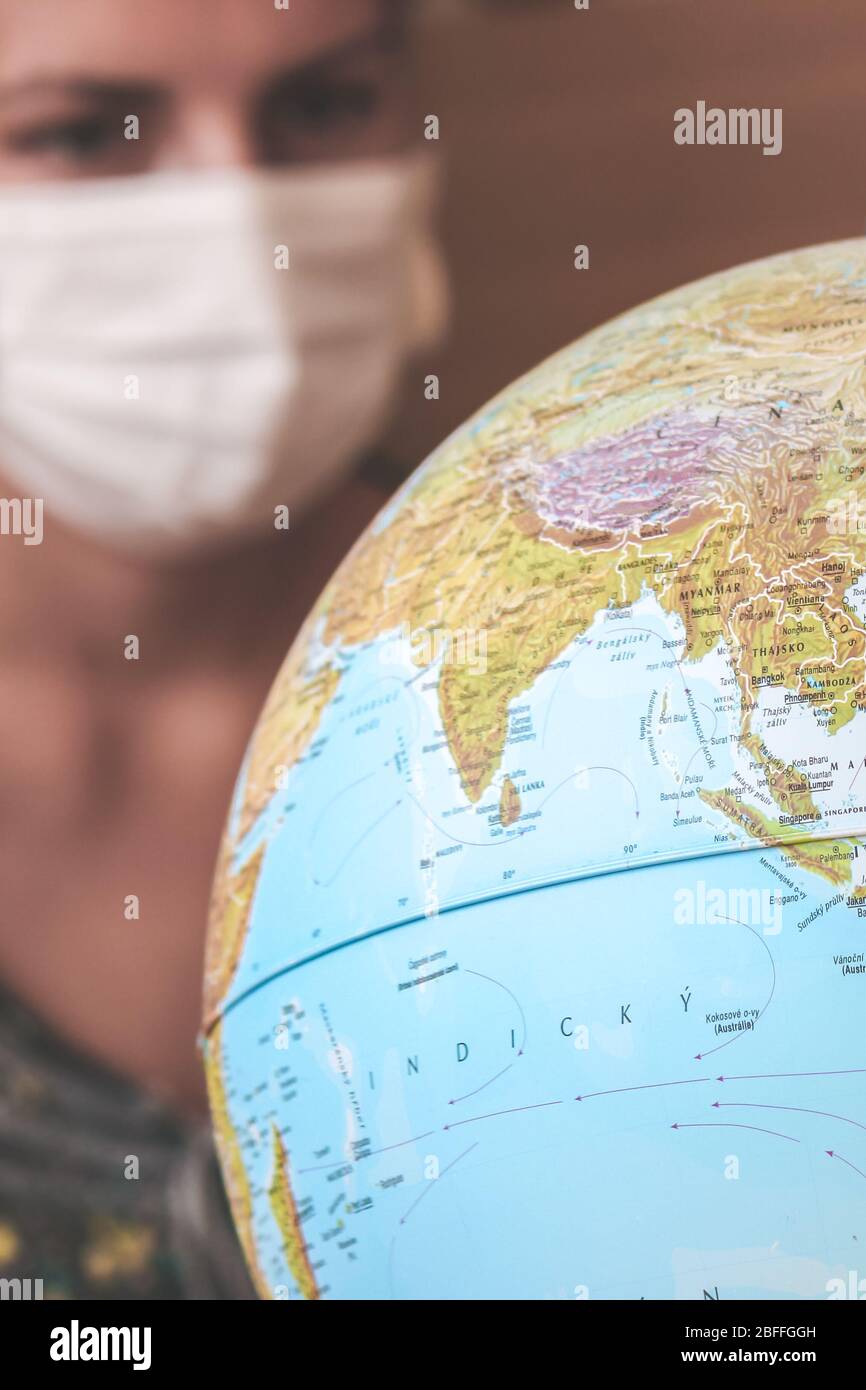 Jeune femme trouble voyageur dans un masque médical regardant le monde entier. Quarantaine du coronavirus. Restrictions de voyage causées par l'éclosion de COVID-19. Voyage annulé. Mise au point sélective. Banque D'Images