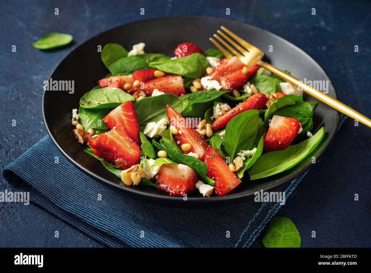 Gros plan de la salade de fraises aux épinards et aux noix de feta ans sur fond bleu Banque D'Images