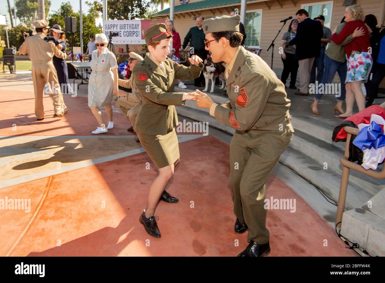 Vêtu de marines américaines, un couple dansa avec enthousiasme un jitterbug de style seconde Guerre mondiale lors des observances de la Journée des anciens combattants à Costa Mesa, Californie. En arrière-plan est une femme dans un uniforme de 'fille' de la Croix-Rouge. Banque D'Images