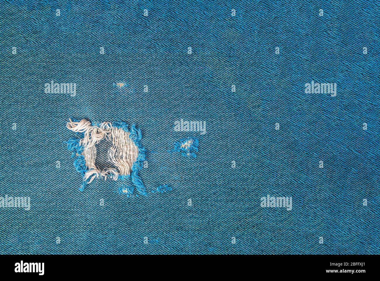 gros plan sur le trou effiloché dans un tissu denim turquoise Banque D'Images