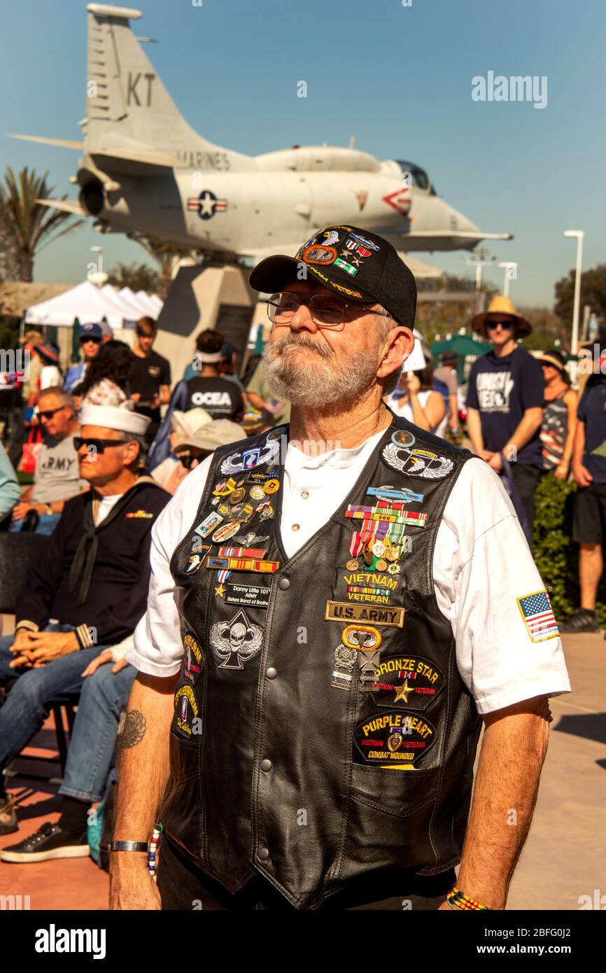 Un vétéran de la guerre du Vietnam montre fièrement un gilet recouvert de décorations de son service de guerre à une célébration patriotique à Costa Mesa, CA. En arrière-plan, un avion Skyhawk de 4 m de l'ère de la guerre du Vietnam. Banque D'Images