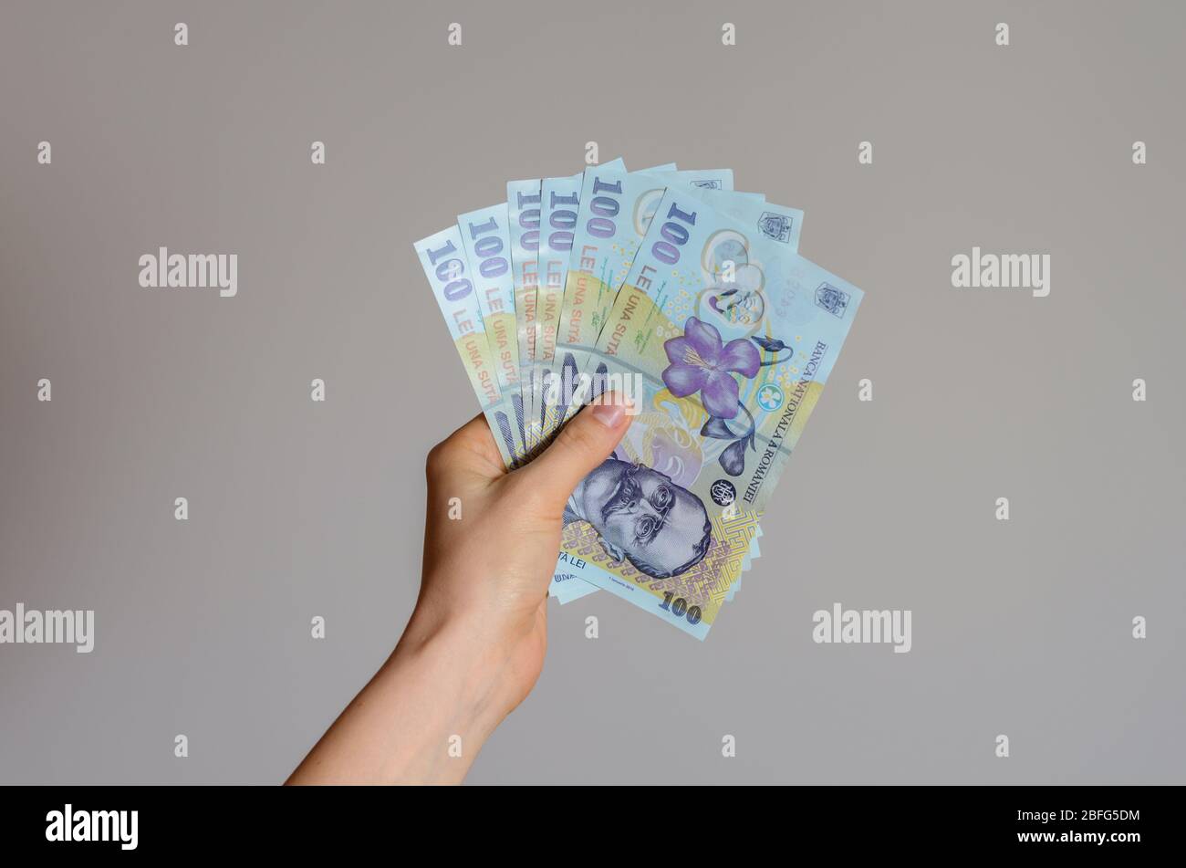 Vue rapprochée de la main d'une femme tenant une pile d'argent de lei roumains sur un fond gris . L'impact économique du coronavirus dans le pays d'Europe la plus orientale Banque D'Images