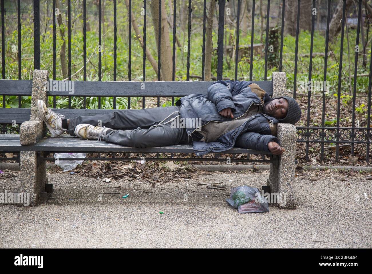 Un homme sans abri dort sur un banc le long de Parkside Avenue pendant la pandémie de Coronavirus à Brooklyn, New York. Banque D'Images