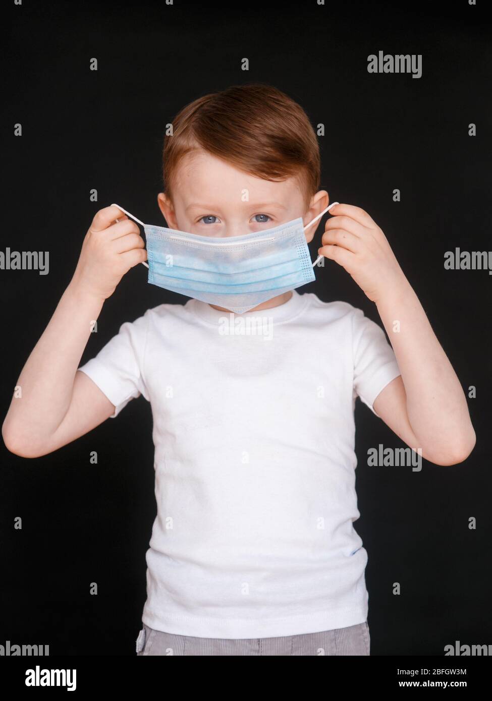 Un Petit Garcon Tient Un Masque Medical Bebe Porte Des Masques Covid 19 Photo Stock Alamy