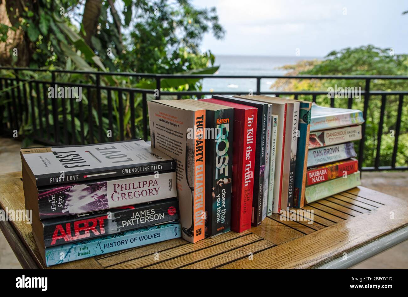 Castara, Trinité-et-Tobago - 12 janvier 2020: Une sélection de livres de fiction populaires sur le dos de papier assis sur une terrasse surplombant la mer des Caraïbes. Banque D'Images