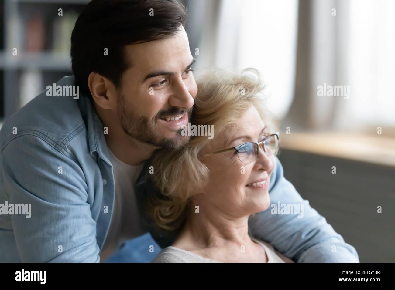 Mère âgée assise à l'intérieur alors que son fils grogner la hople Banque D'Images