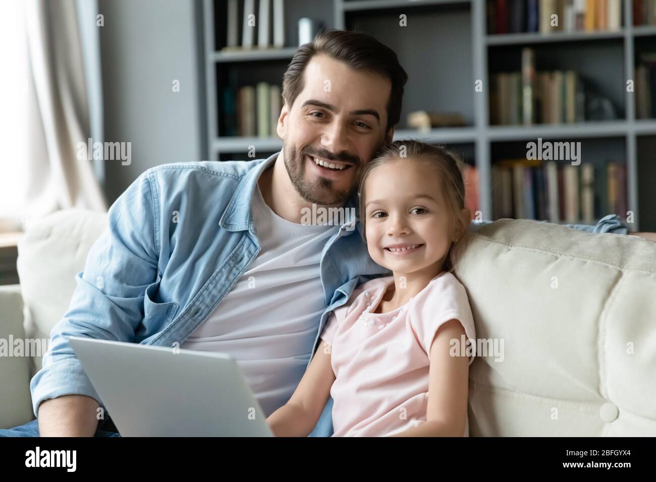 Père et petite fille assis sur le canapé avec ordinateur portable Banque D'Images