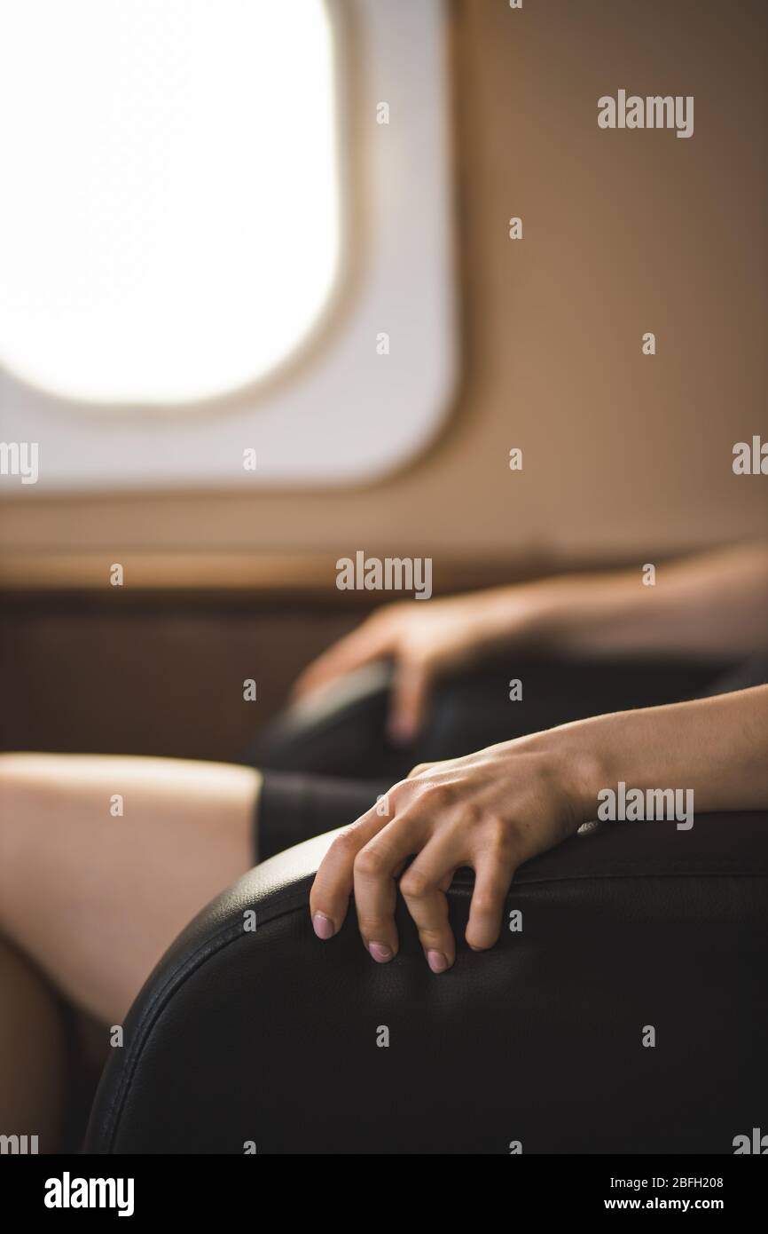 Photo verticale courte d'une femme d'affaires avec peur de vol dans un jet privé. Foyer sélectif de la femme terrifiée assis encombrer les bras de la chaise dedans Banque D'Images