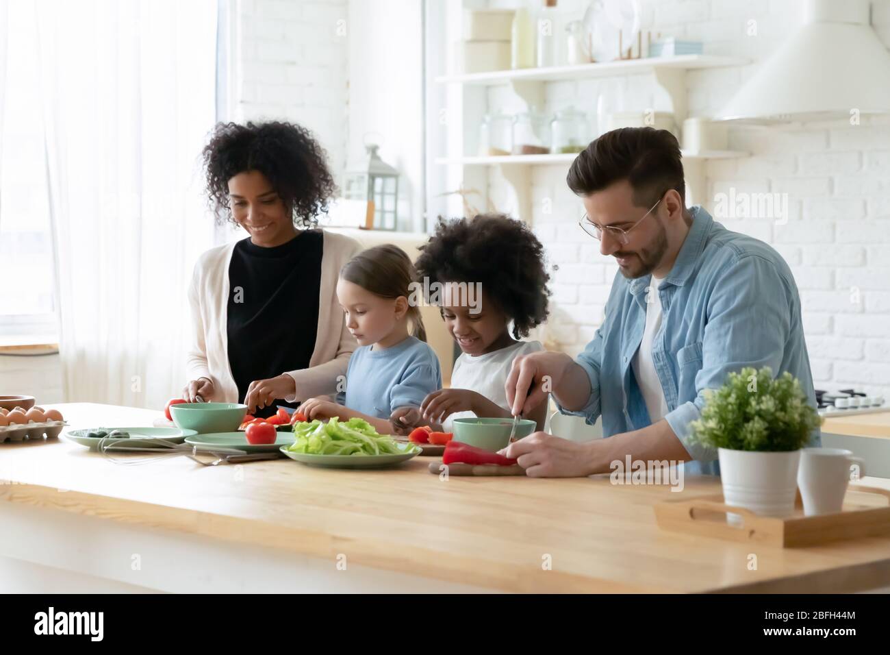 Famille multiraciale souriante avec petit déjeuner de cuisine pour enfants ensemble Banque D'Images