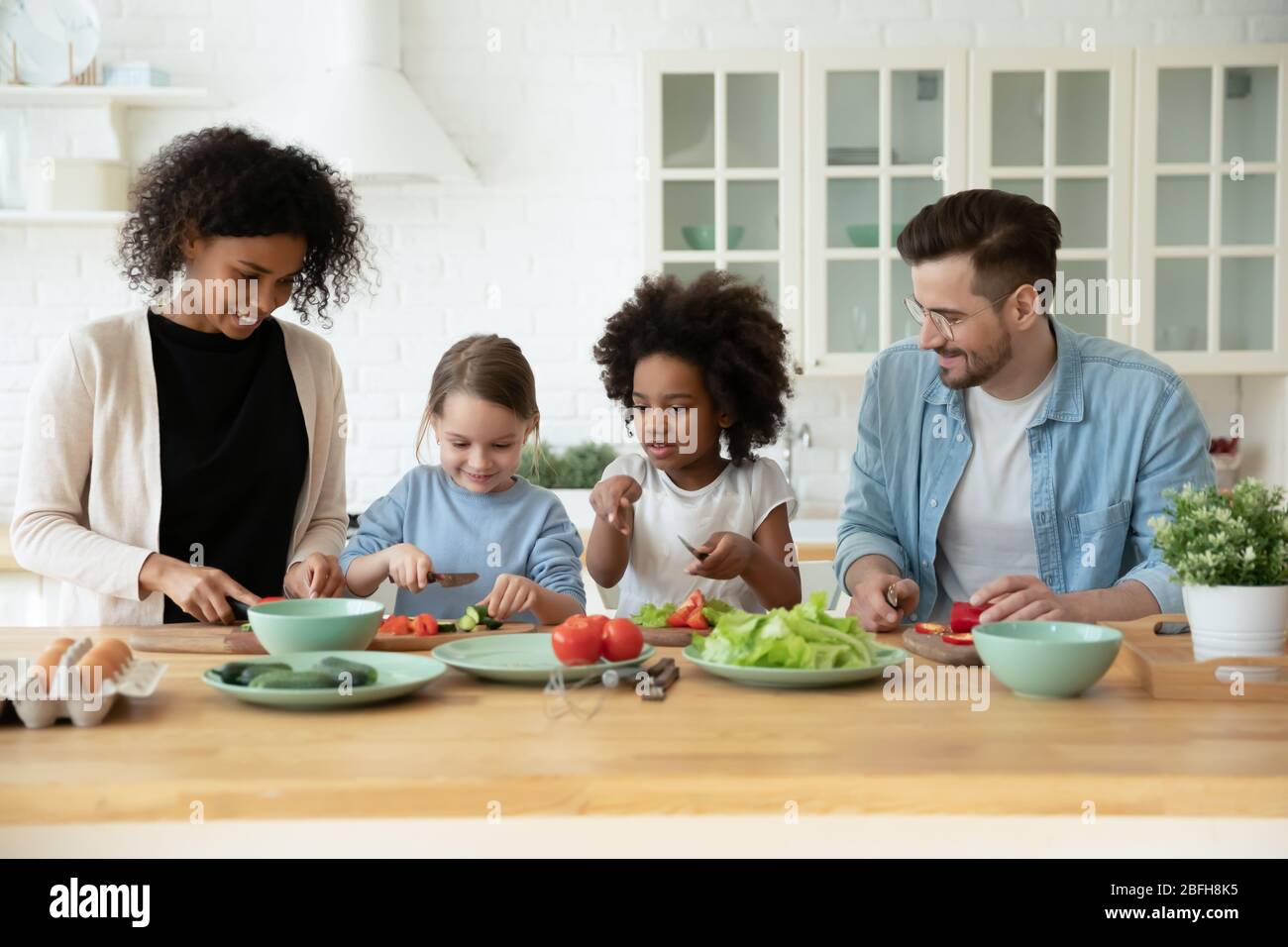 Jeune famille multiraciale avec des enfants cuisinant ensemble à la maison Banque D'Images